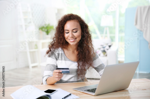 Beautiful young woman using credit card and laptop for online shopping