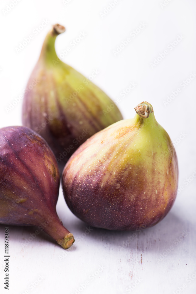 close up of organic, fresh figs grouped and isolated on rustic white wooden board, vertical close up of organic, fresh figs grouped and isolated on rustic white wooden board, vertical