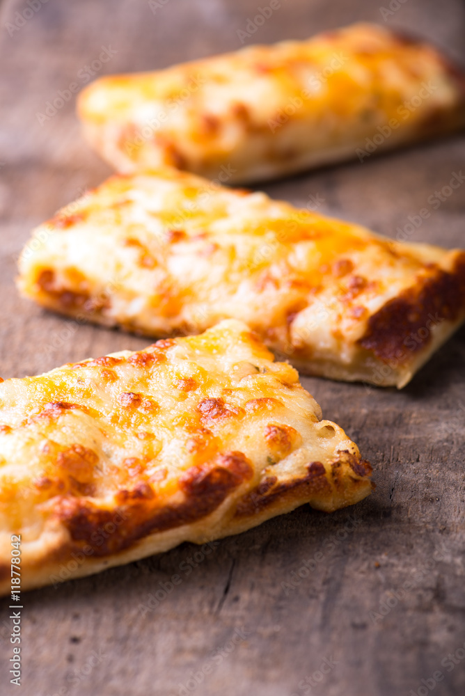 close up of cheese pizza slices, isolated flat on brown rustic wooden background, vertical