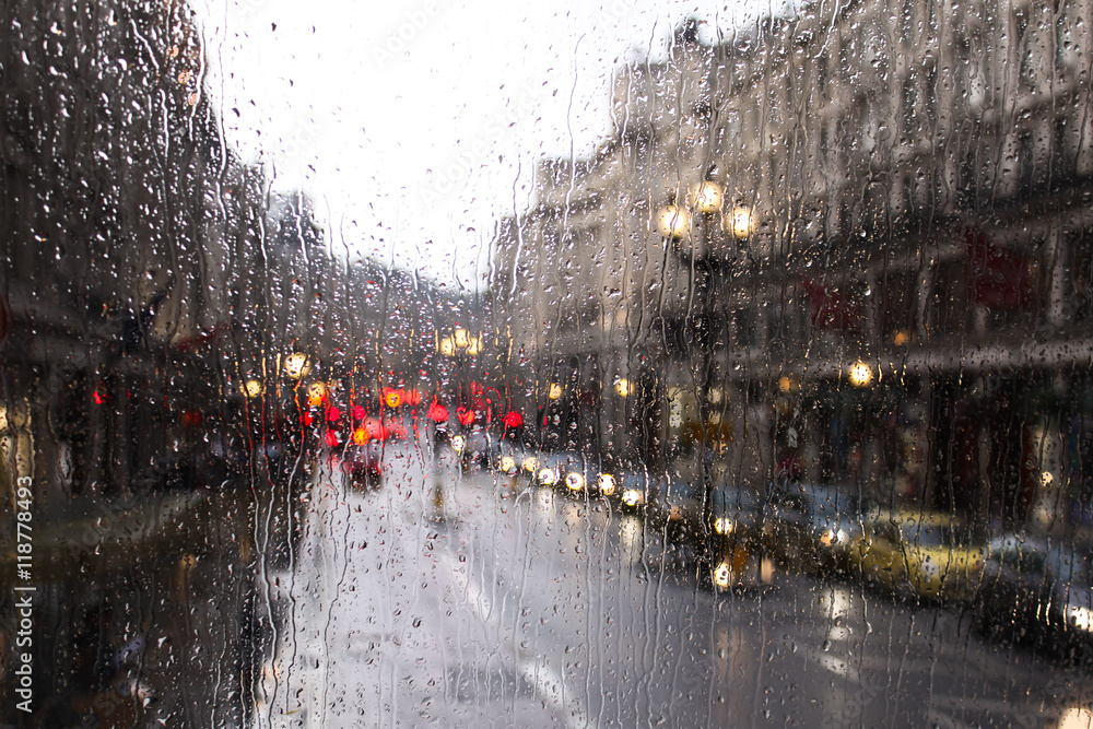Obraz premium niewyraźny widok ruchu drogowego w Londynie w deszczowy dzień przez okno autobusu. krople deszczu na szybie autobusu