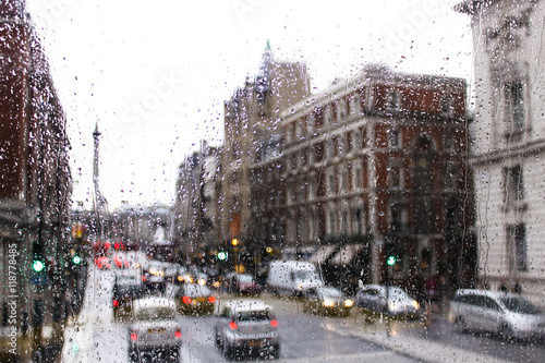 blurred view of road traffic in London on a rainy day through the bus window. raindrops on the glass window of the bus