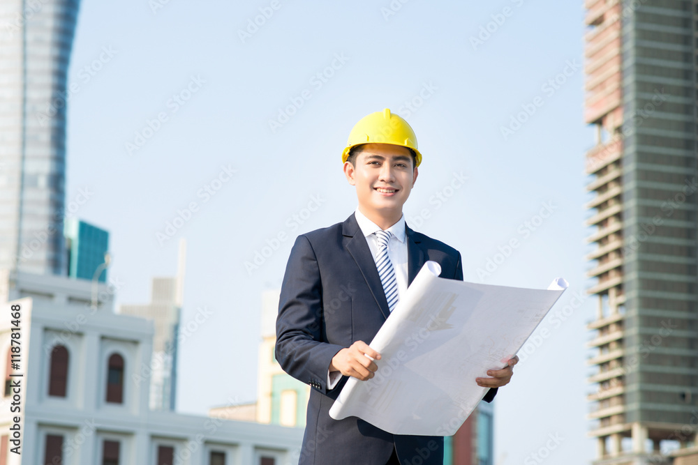 Architect holding blueprints and looking at the building at the Architect holding blueprints and looking at the building at the