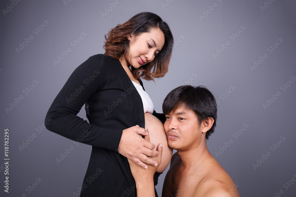 Fototapeta premium young couple: pregnant mother and happy father on gray backgroun