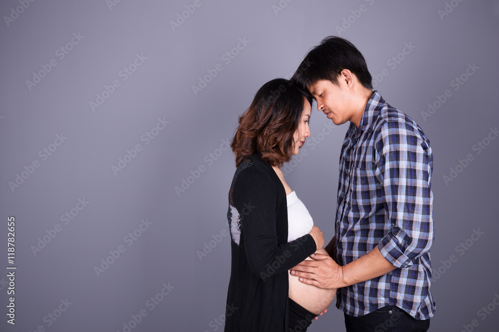 young couple: pregnant mother and happy father on gray backgroun young couple: pregnant mother and happy father on gray backgroun