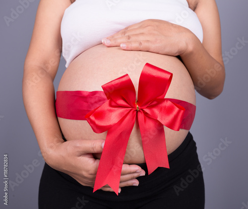 Wallpaper Mural close up pregnant woman with red ribbon gift on belly Torontodigital.ca