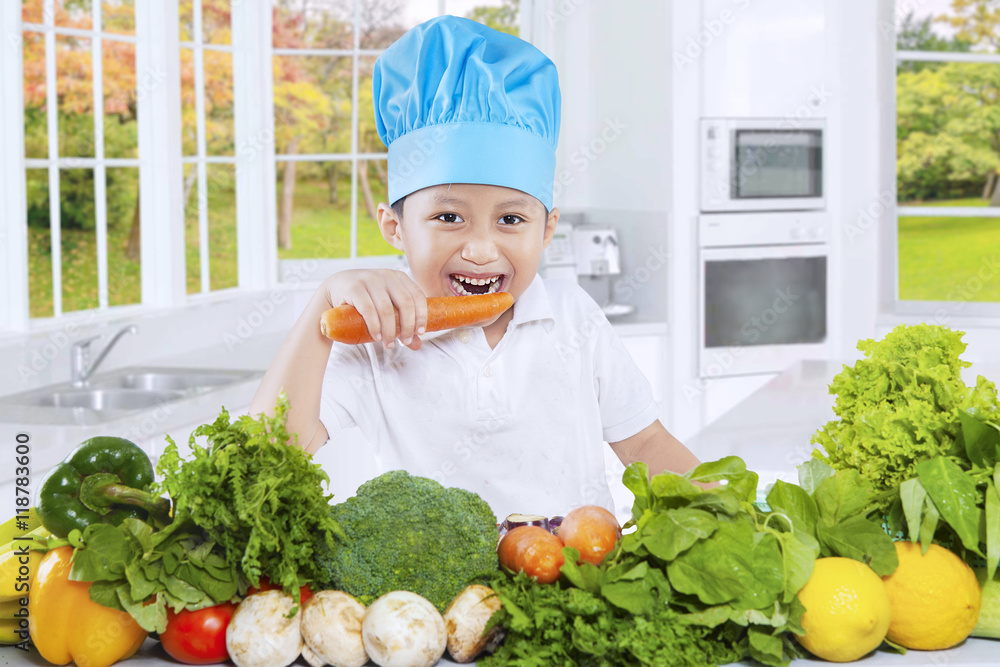 Boy eats a carrot in the kitchen Boy eats a carrot in the kitchen