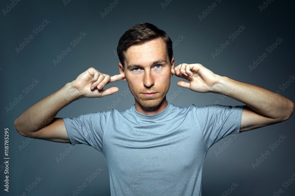 Young man stopped his ears with fingers. Young man stopped his ears with fingers.