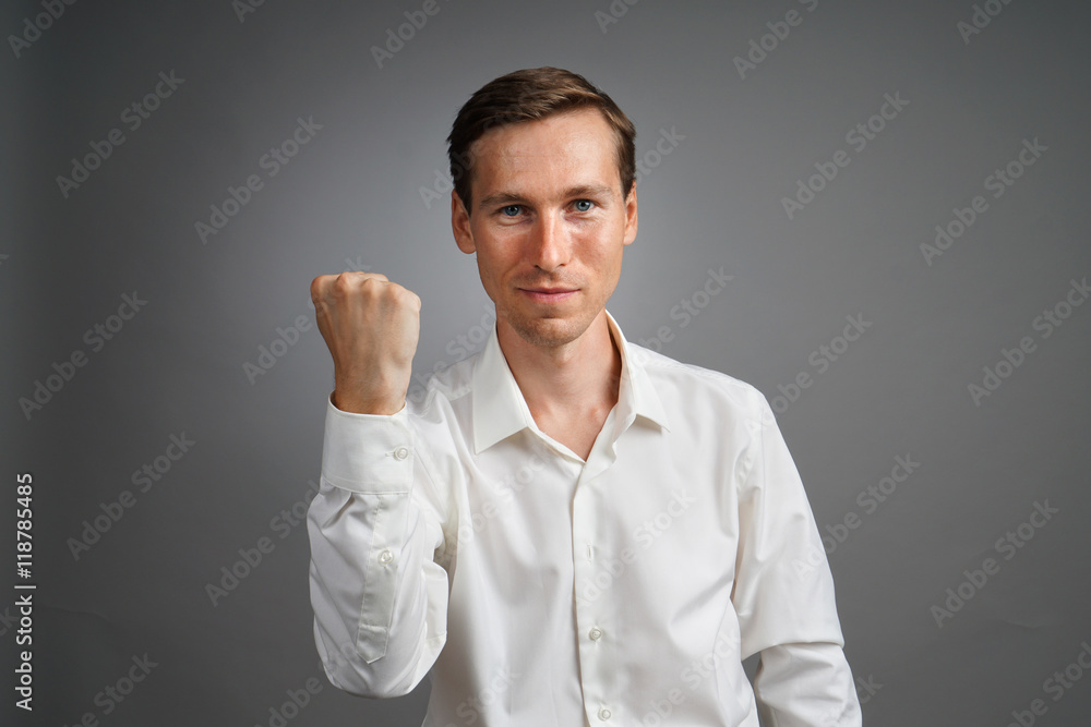 Gesture of success. Smiling man in white shirt with raised hand. Gesture of success. Smiling man in white shirt with raised hand.