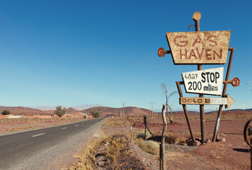Deserted road  and tall vintage gas sign  in typical Moroccan landscape near Ouarzazate,  Morocco.