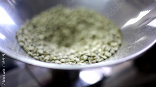 Green coffee beans are poured into a roasting pan