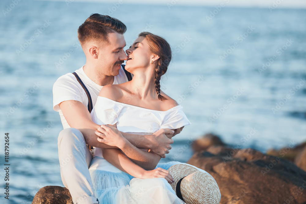 Happy young romantic couple relaxing on the beach and watching the sunset