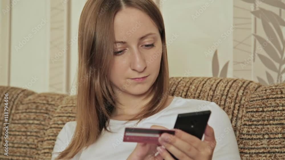 Female buying goods from the internet on her smartphone with her credit card. Young woman caucasian hands entering number security code from credit card on mobile phone Female buying goods from the internet on her smartphone with her credit card. Young woman caucasian hands entering number security code from credit card on mobile phone