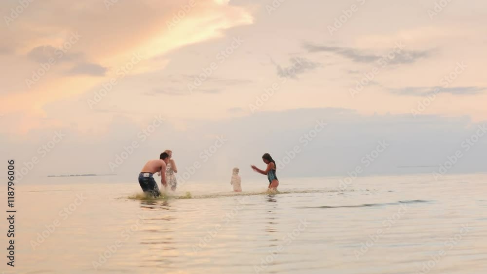 Children and adults play in the water, laughing, splash water at each other Children and adults play in the water, laughing, splash water at each other