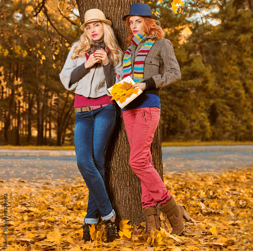 Fall Fashion. Woman in Stylish Autumn Outfit walk in park. Sisters