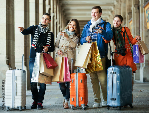 Travellers with shopping bags on street.