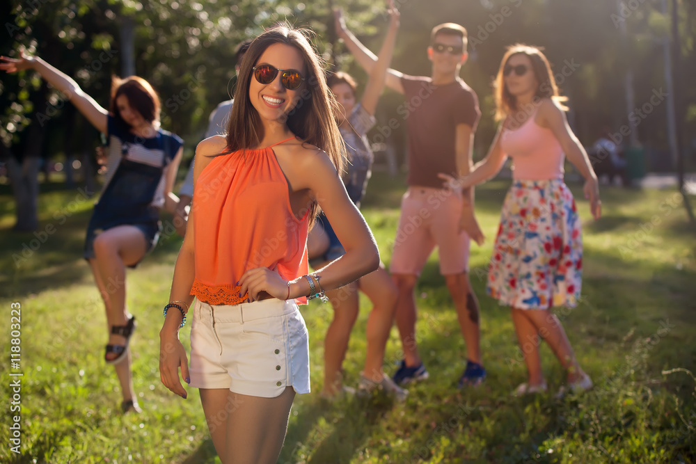 Fototapeta premium summer holidays and teenage concept - young girl out with friends outside. Portrait of a young girl and his friends in the background.