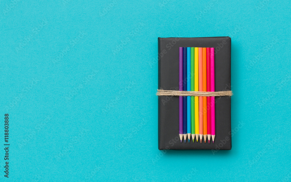 Colorful school and office supplies - pencils and ruler on black book and blue background. Top view with copy space. Colorful school and office supplies - pencils and ruler on black book and blue background. Top view with copy space.