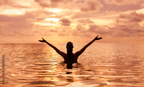 Feeling stress free. Happy woman enjoying a swim during sunset.  photo