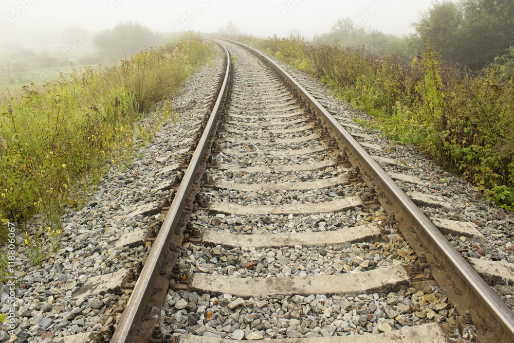 Empty railroad track going into a fog. Perspective view.