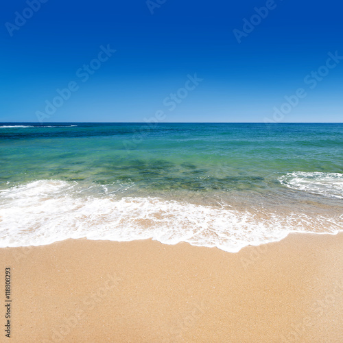 Calm sea with golden sand and blue sky