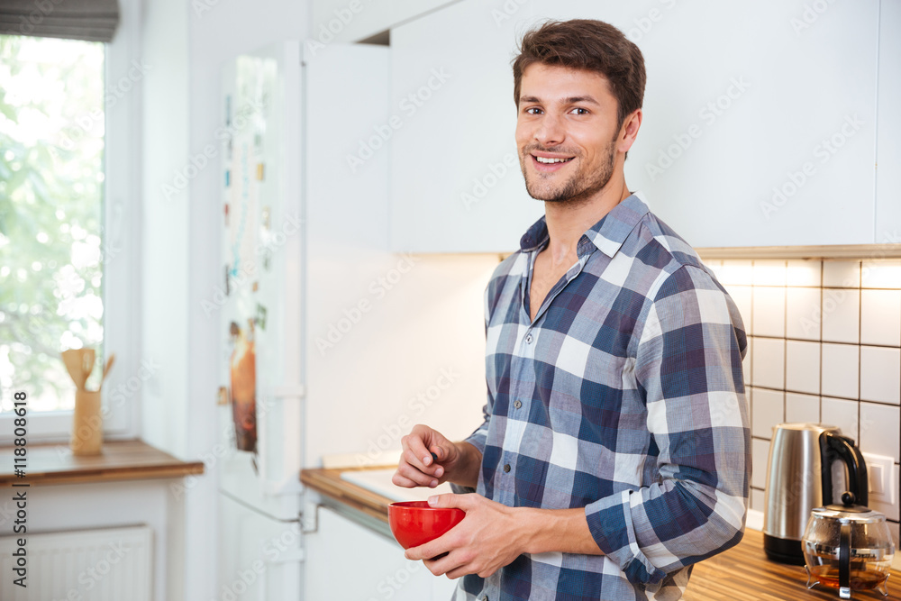 Smiling young man standing on the kitchen Smiling young man standing on the kitchen