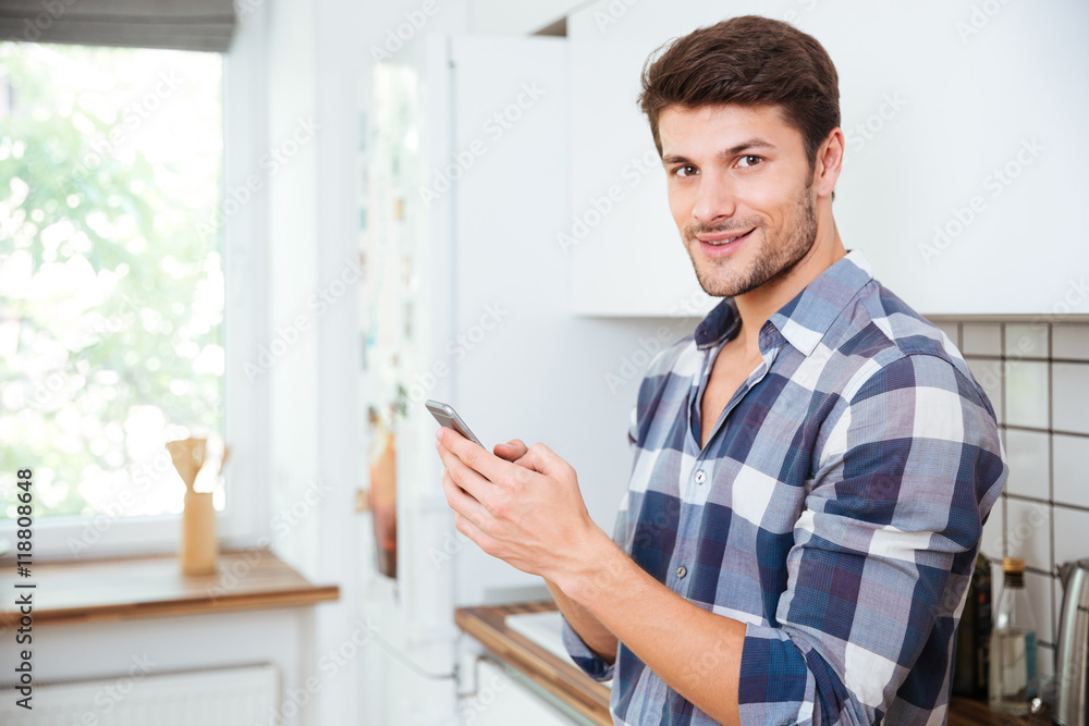 Happy young man using cell phone on the kitchen Happy young man using cell phone on the kitchen