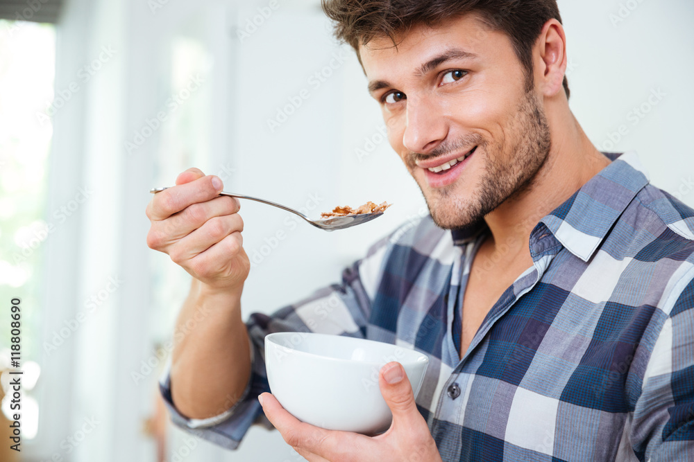 Happy young man eating cereals with milk at home Happy young man eating cereals with milk at home