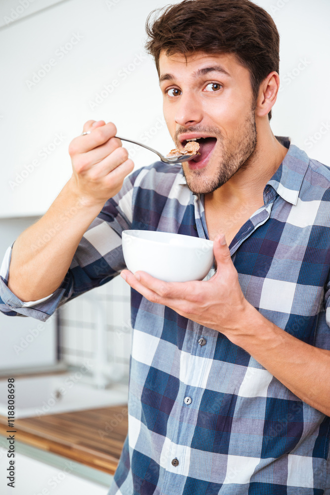 Man having breakfast and eating cereals with milk on kitchen Man having breakfast and eating cereals with milk on kitchen