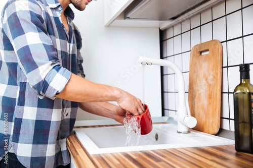 Man in checkered shirt washing dishes on the kitchen photo