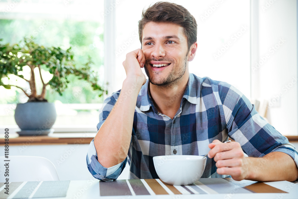 Happy man using smartphone and having breakfast on the kitchen Happy man using smartphone and having breakfast on the kitchen