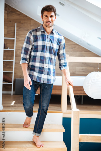 Attractive young man walking barefoot on stairs at home © Drobot Dean