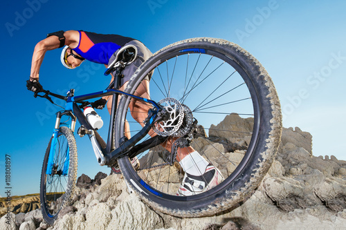 Man carrying a bike on the rocky terrain
