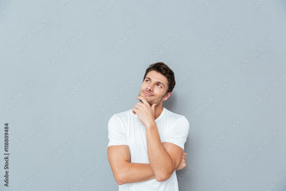 Pensive attractive young man smiling and thinking - obrazy, fototapety, plakaty 
