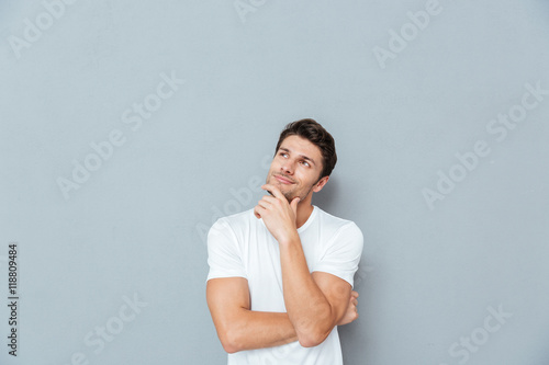 Pensive attractive young man smiling and thinking photo