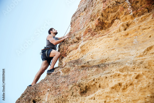 Young man climbing natural rocky wall