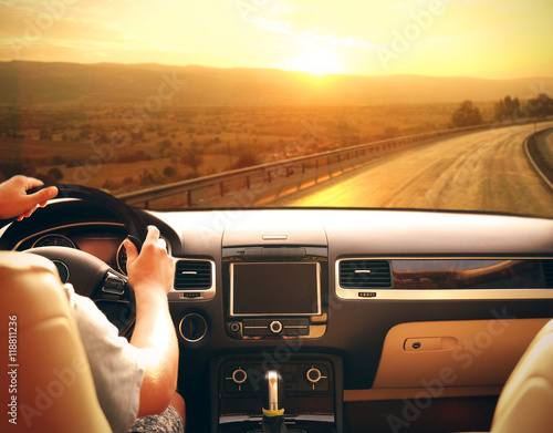 Male hands on car steering wheel. View from car windshield to road and beautiful landscape. photo