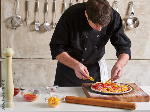 Restaurant hotel private chef preparing pizza adding toppings