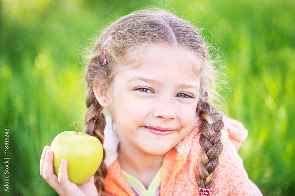 Little cute girl on a background of green grass with an apple Little cute girl on a background of green grass with an apple