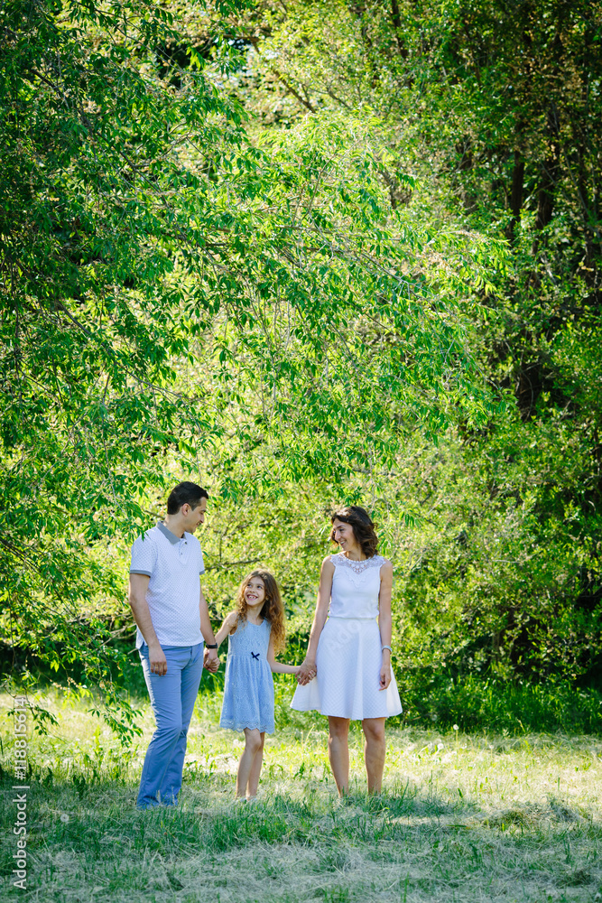 Young beautiful family three playing talking in the park mother father daughter Young beautiful family three playing talking in the park mother father daughter
