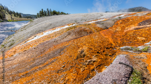 The bright colors of the river shore. Runoff flows into the Firehole River. Midway Geyser Basin, Yellowstone National Park, Wyoming