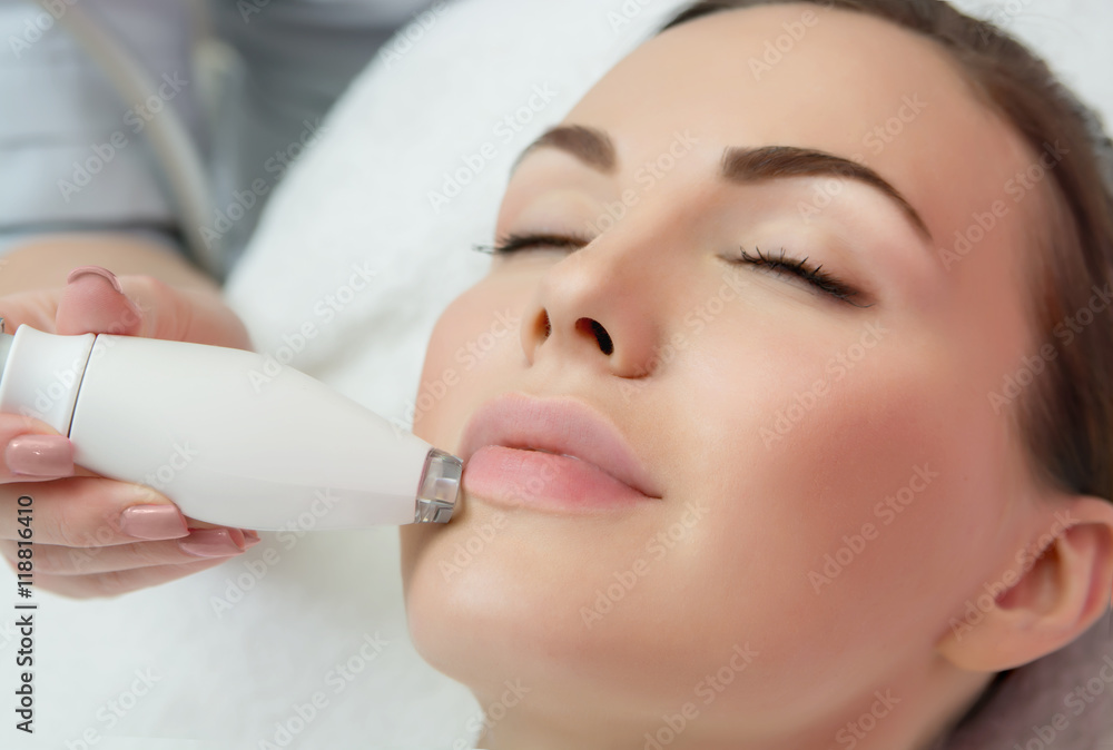 Therapist beautician makes a rejuvenating facial massage for the  woman