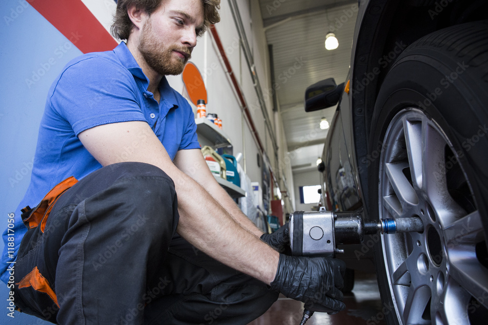 Mechanic fixing a car wheel in a workshop Mechanic fixing a car wheel in a workshop