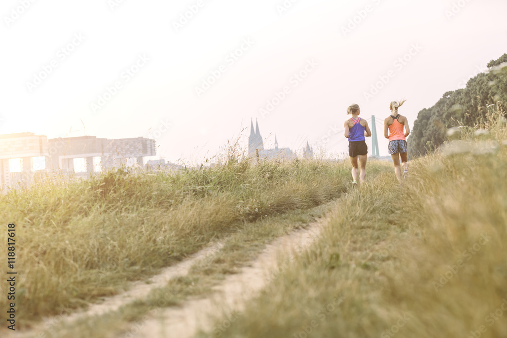 Two young women running on field path Two young women running on field path