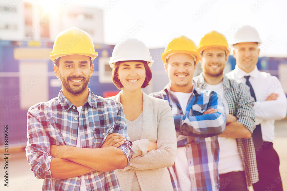 group of smiling builders in hardhats outdoors group of smiling builders in hardhats outdoors