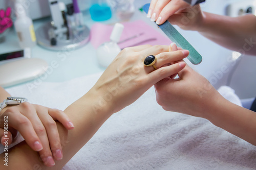 Woman hands in a nail salon receiving a manicure by a beautician