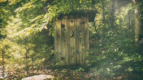 Rural Outhouse. A typical old fashioned outhouse bathroom in a wooded, forest area. photo