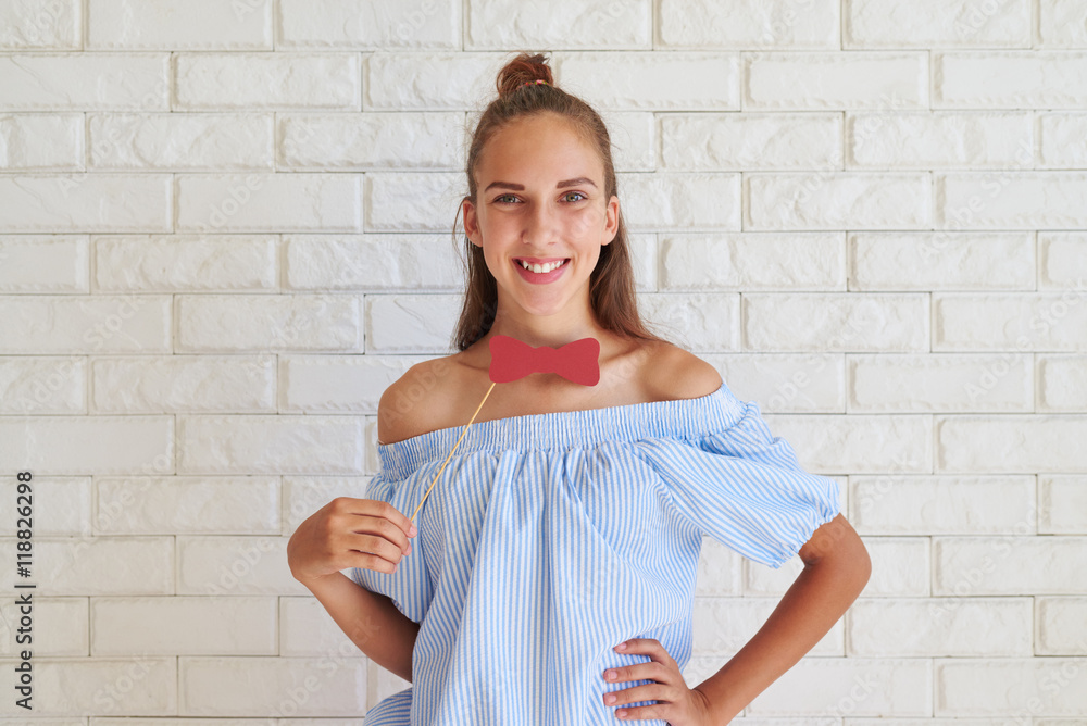 Close-up of young pretty girl smiling and holding paper bow-tie Close-up of young pretty girl smiling and holding paper bow-tie