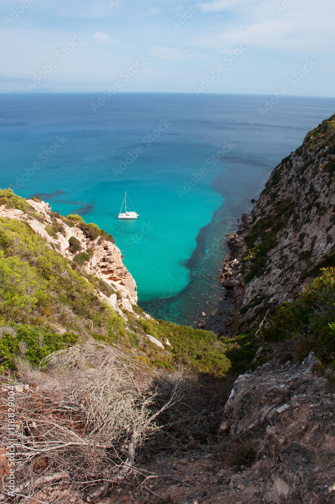 Formentera, Isole Baleari: un catamarano nel Mar Mediterraneo con vista sulla macchia mediterranea e le scogliere il 5 settembre 2010