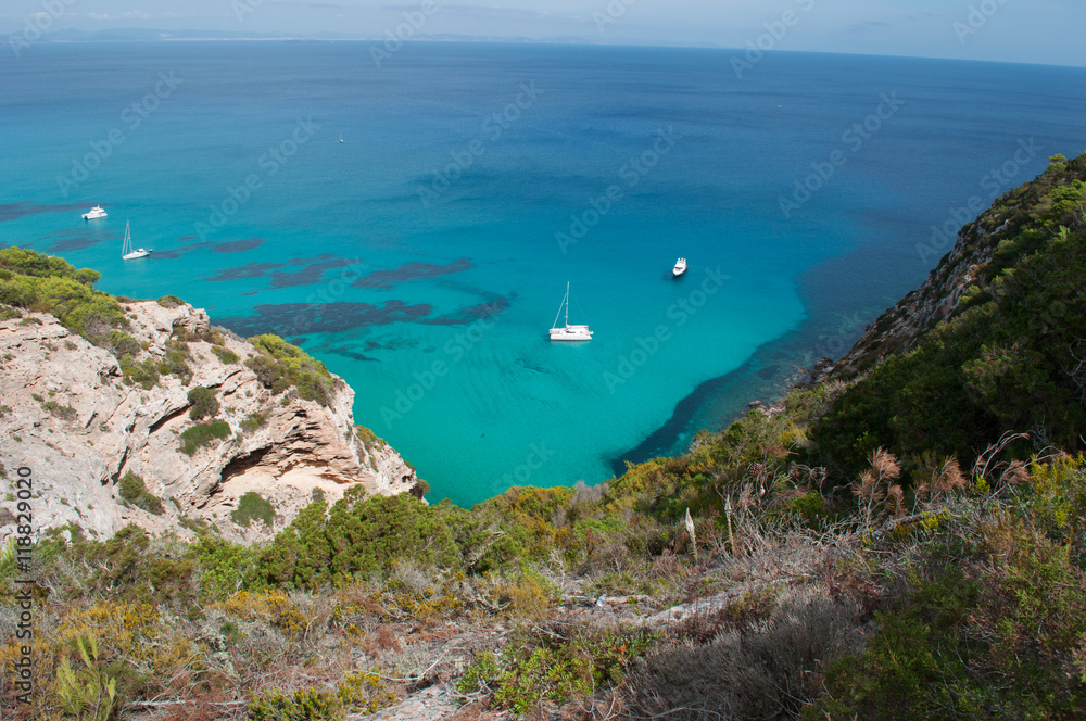 Fototapeta premium Formentera, Isole Baleari: un catamarano e un motoscafo nel Mar Mediterraneo con vista sulla macchia mediterranea e le scogliere il 5 settembre 2010