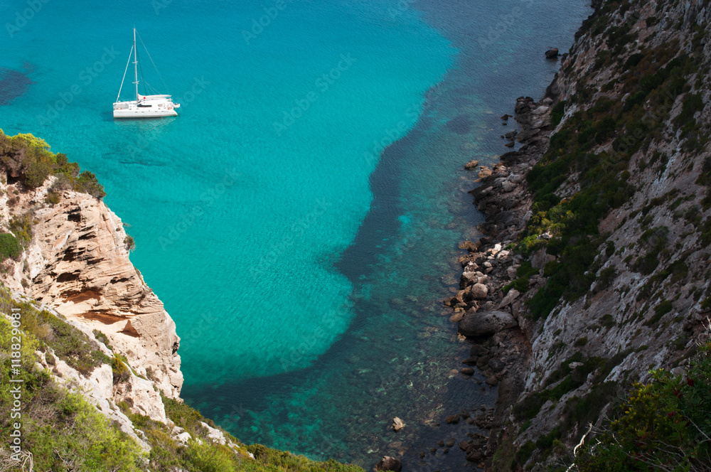 Formentera, Isole Baleari: un catamarano nel Mar Mediterraneo con vista sulla macchia mediterranea e le scogliere il 5 settembre 2010